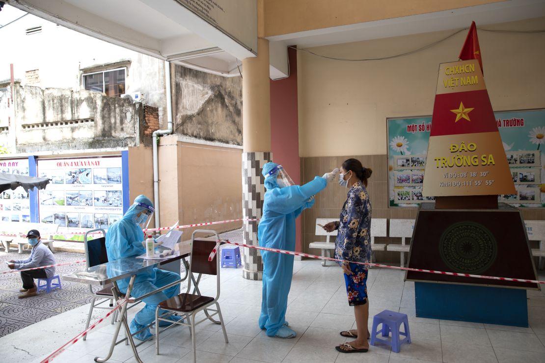 A health worker checks the temperature of a member of the public at a Covid-19 vaccination center in Ho Chi Minh City on August 5, 2021. 