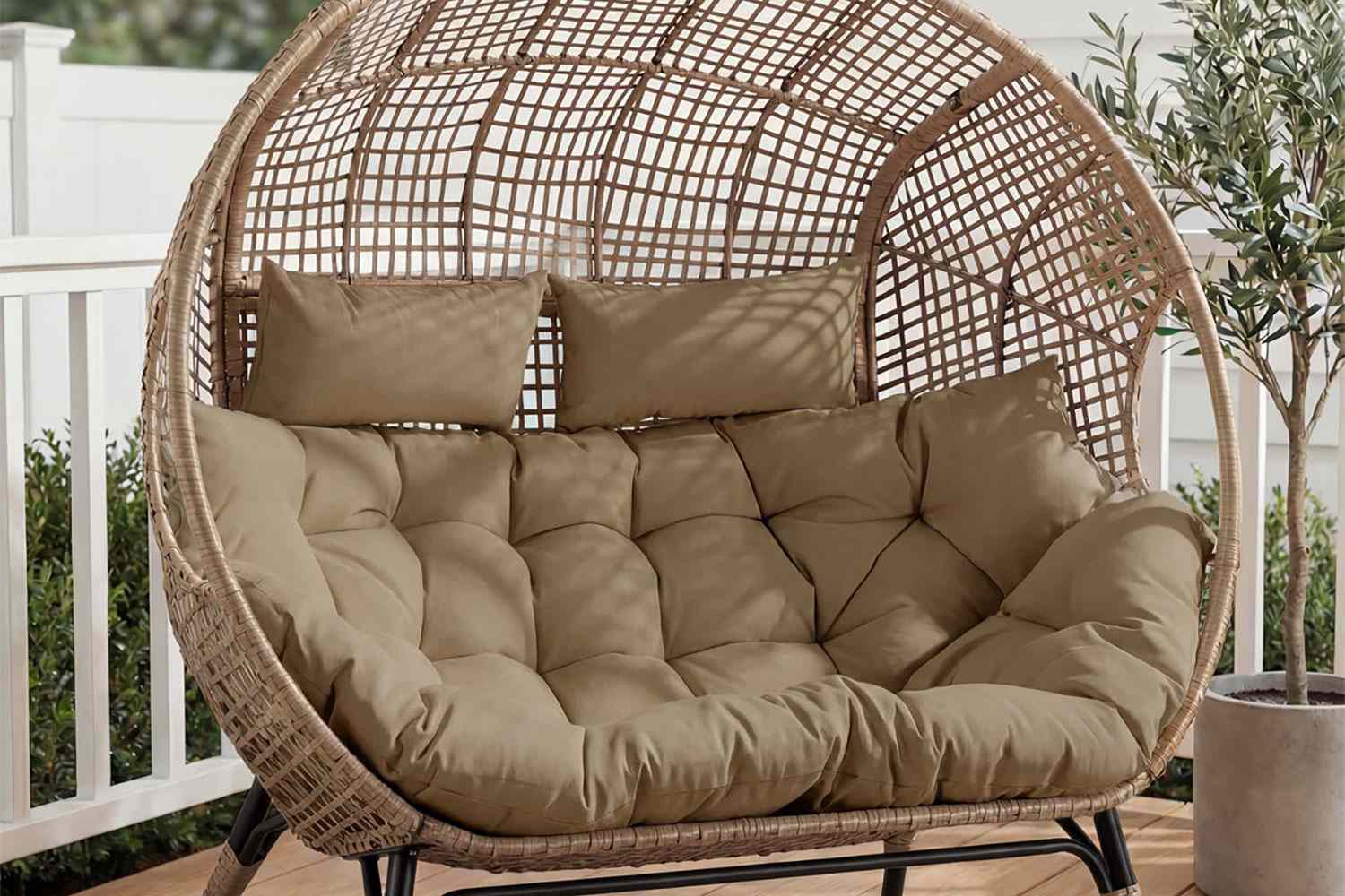 A wicker rattan eggshaped chair with cushions on a deck